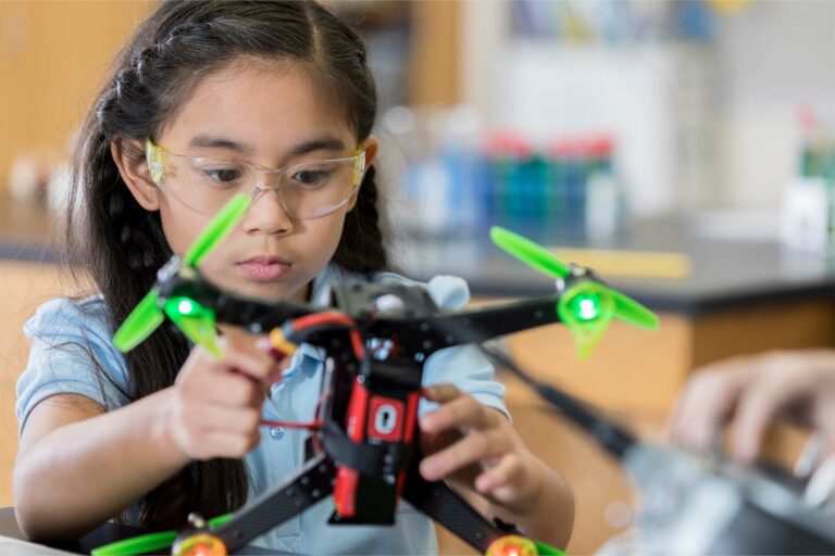Smart STEM schoolgirl concentrates as she finishes building a drone during robotics class.
